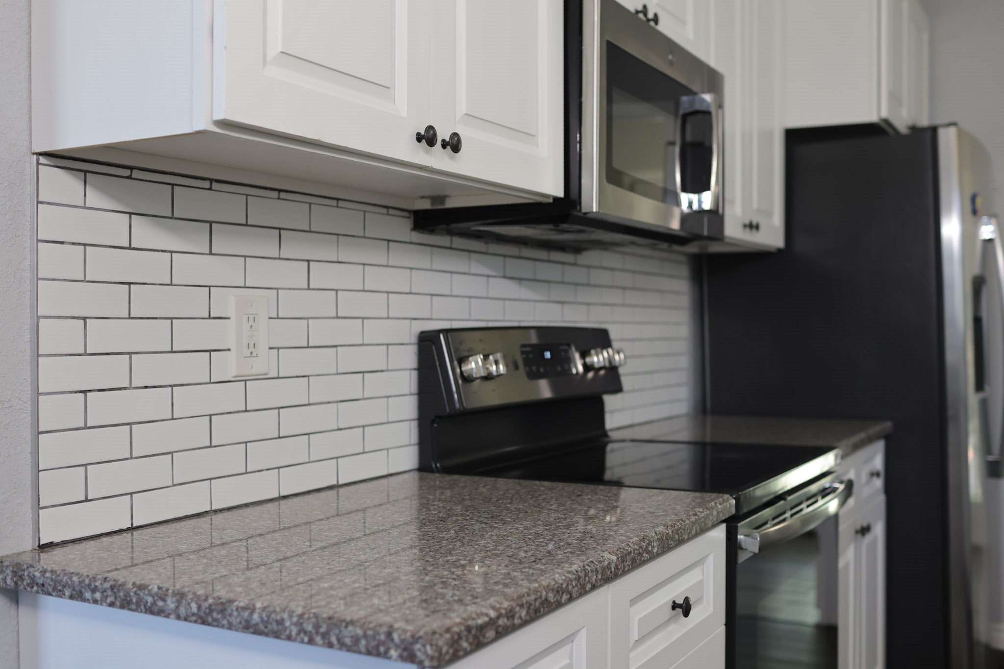 407 Tamarind Street Lake Jackson, TX 77566 - Photo 16 of 36 This kitchen features modern stainless steel appliances, white cabinetry, and a stylish subway tile backsplash. The granite countertop adds a touch of elegance and durability.