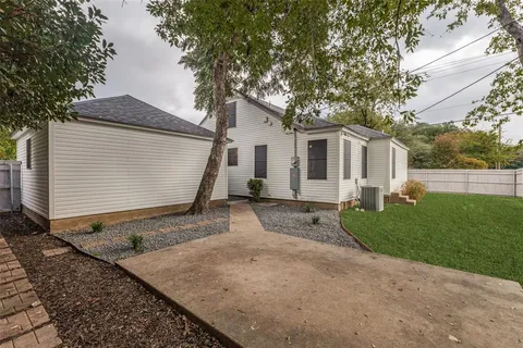 a view of a house with a small yard plants and a large tree