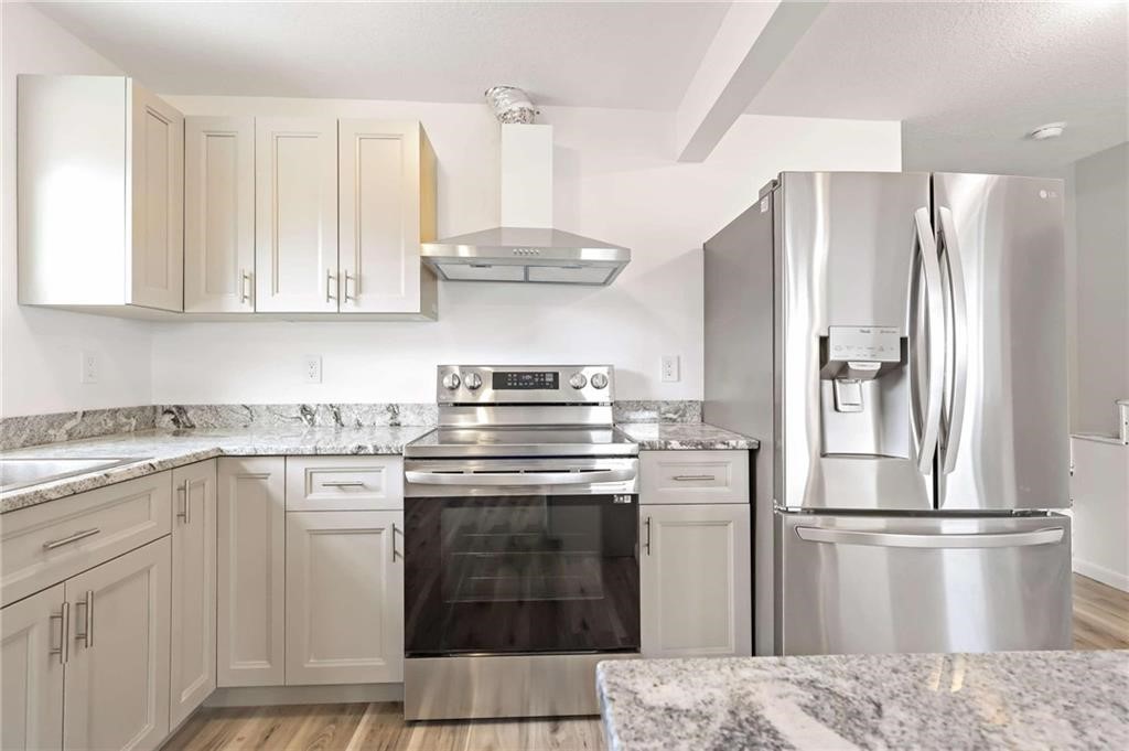 9185 Highway 1 Sebastian, FL 32958 - Photo 18 of 30 a kitchen with stainless steel appliances granite countertop a refrigerator a stove and white cabinets with wooden floor