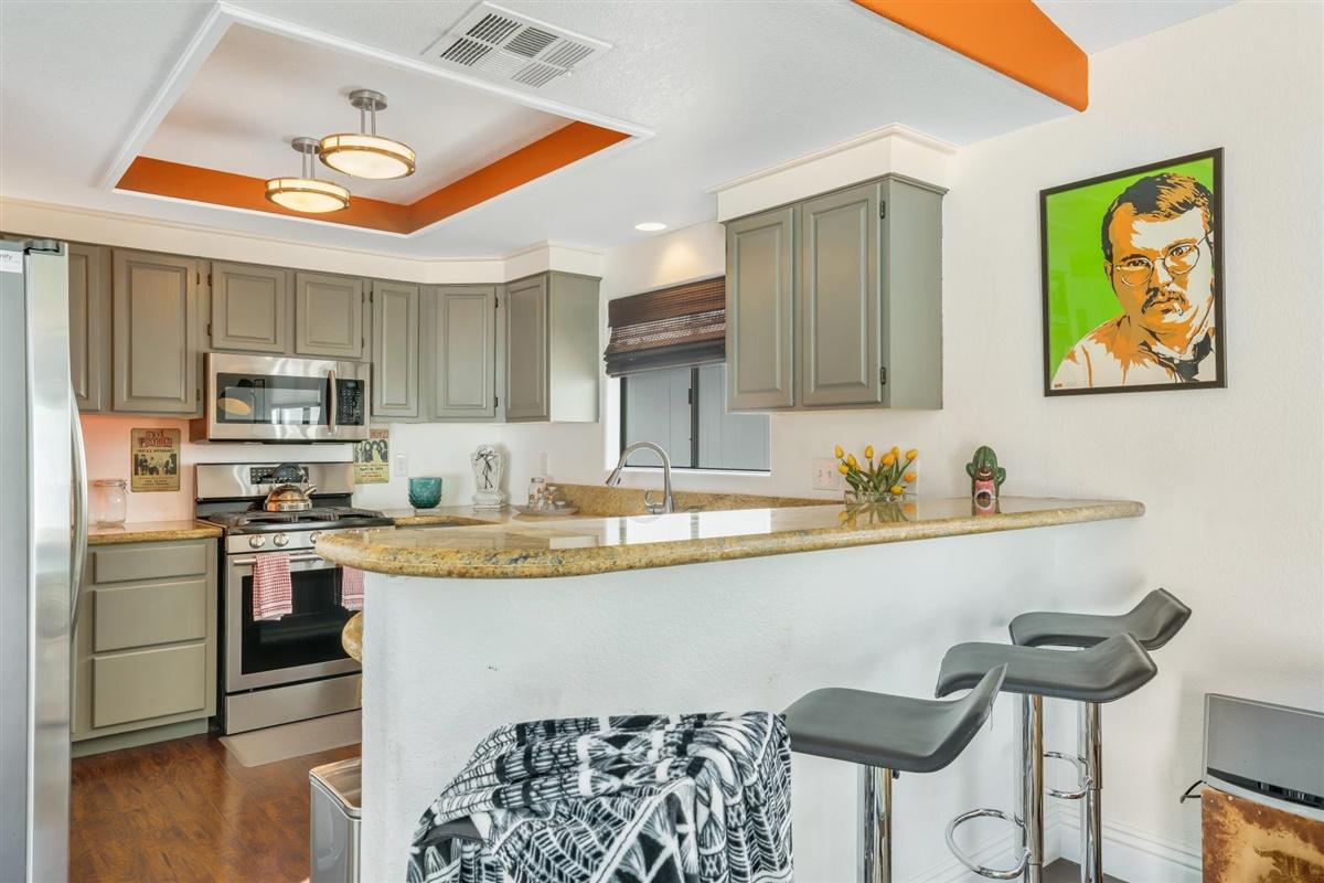 52695 Avenida Bermudas La Quinta, CA 92253 - Photo 29 of 49 a kitchen with stainless steel appliances granite countertop a stove top oven a sink a dining table and chairs with wooden floor