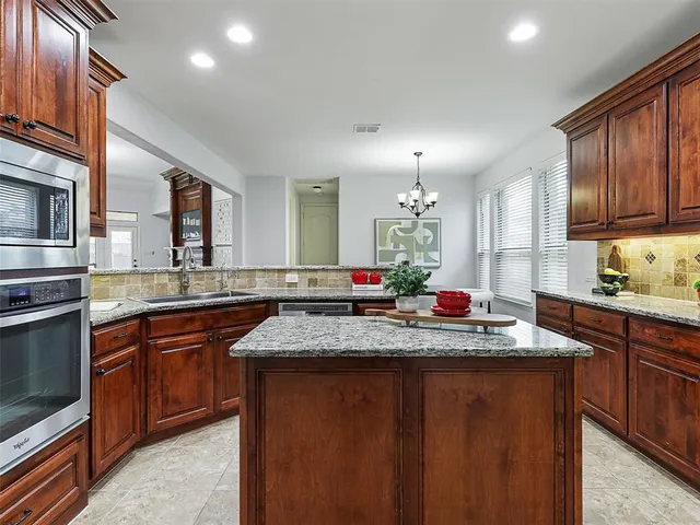 a kitchen with kitchen island granite countertop wooden cabinets and stainless steel appliances