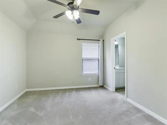 an empty room with a fan & a window