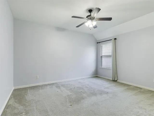 an empty room with chandelier fan and windows