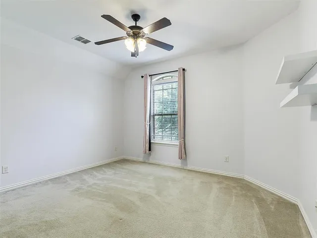 an empty room with a chandelier fan and windows