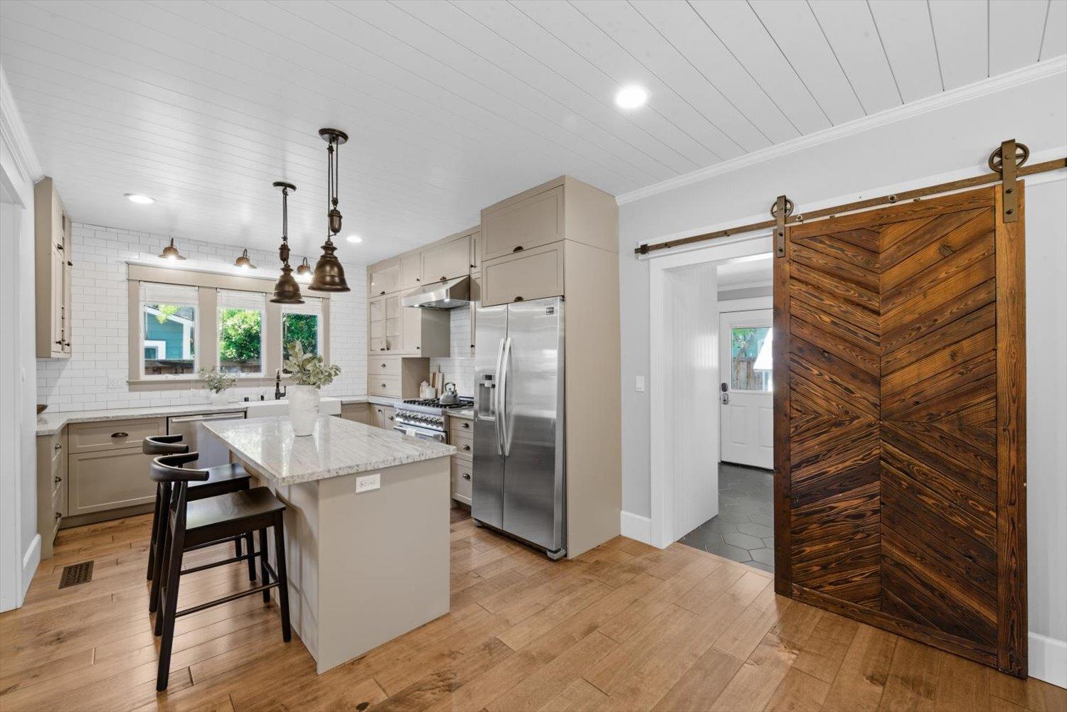 1121 4th Street Davis, CA 95616 - Photo 14 of 40 a kitchen with stainless steel appliances a refrigerator a sink dishwasher a stove and a dining table with wooden floor