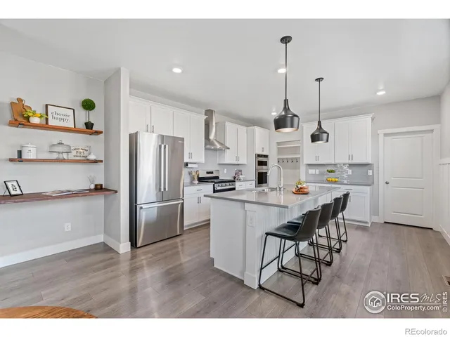 a kitchen with refrigerator and wooden floor
