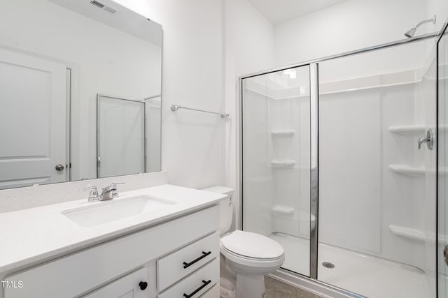 a bathroom with a shower sink vanity mirror and toilet