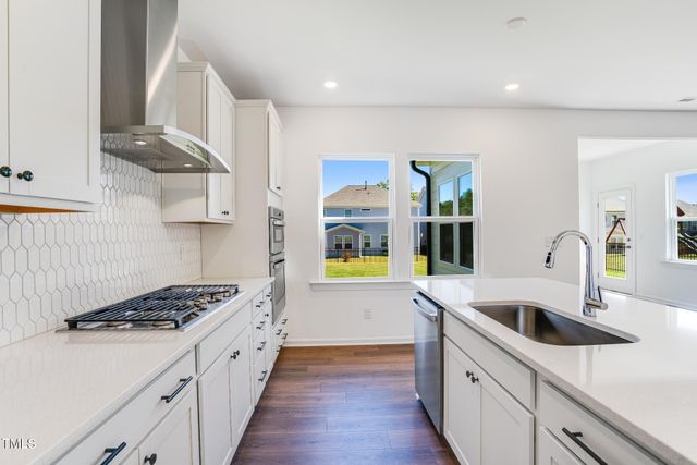 a kitchen with stainless steel appliances a sink a stove and wooden cabinets