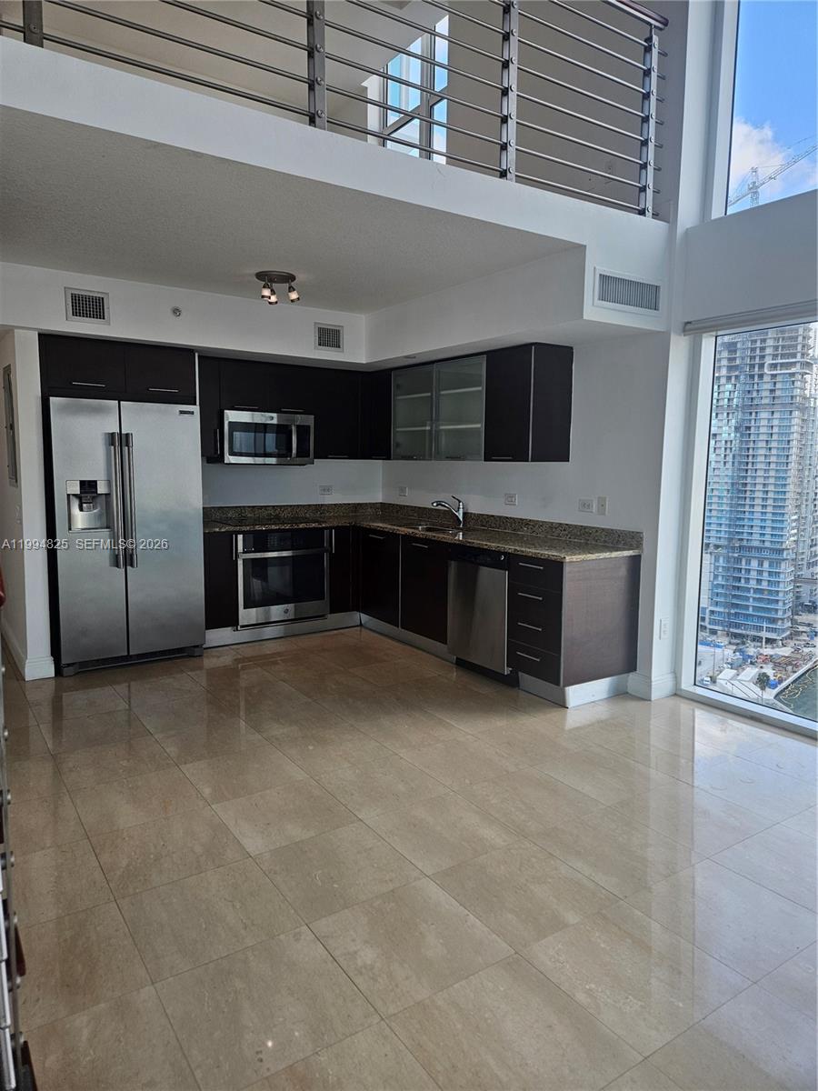 41 Southeast 5th Street, Unit 1517 Miami, FL 33131 - Photo 12 of 62 a living room with stainless steel appliances kitchen island granite countertop a refrigerator a stove and a sink with wooden cabinets