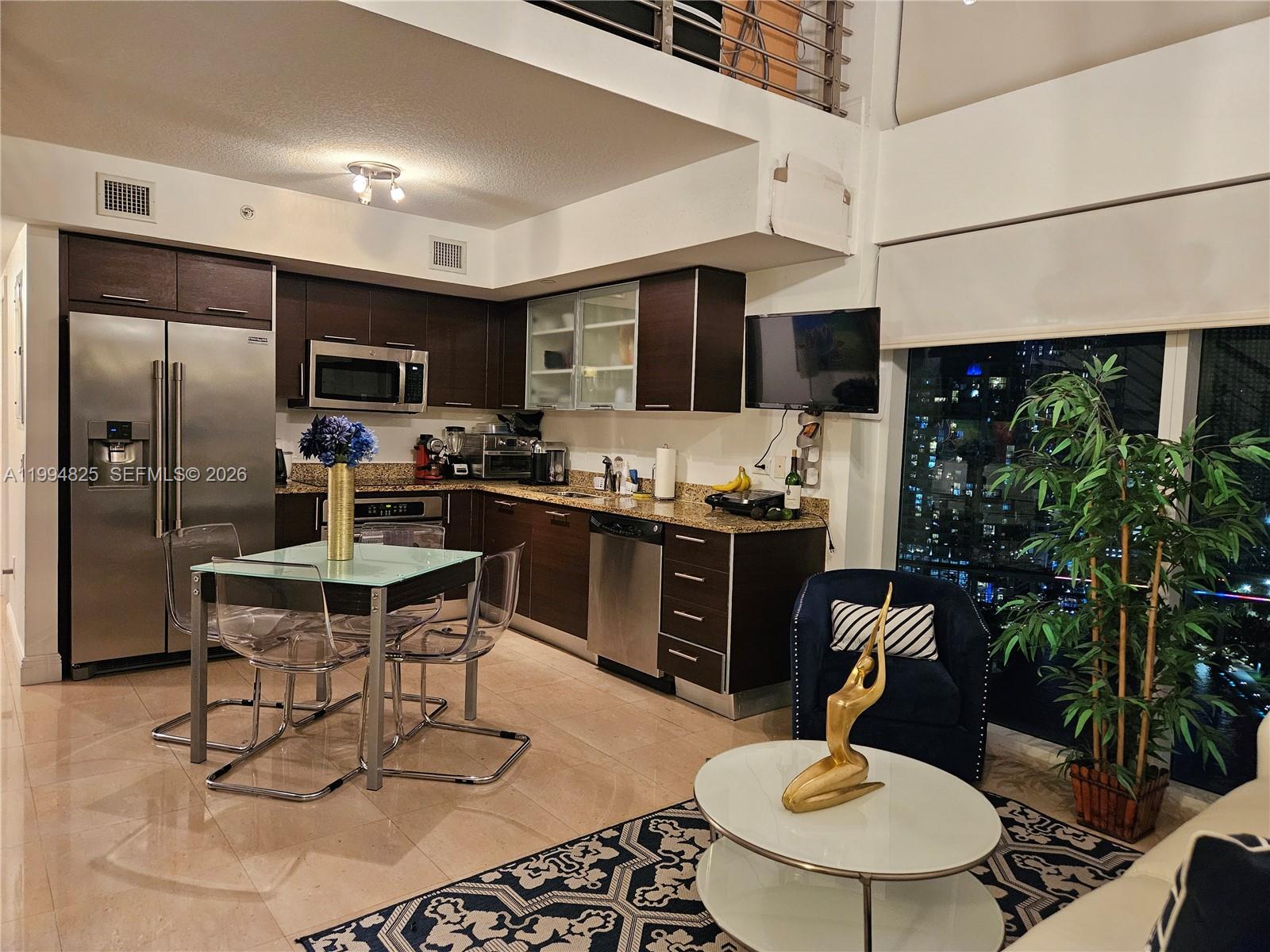 41 Southeast 5th Street, Unit 1517 Miami, FL 33131 - Photo 18 of 62 a kitchen with stainless steel appliances kitchen island granite countertop a sink a stove a dining table and chairs