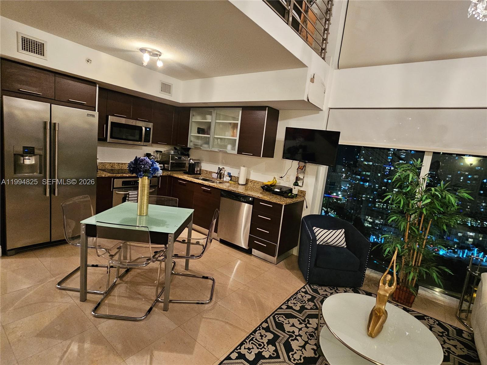 41 Southeast 5th Street, Unit 1517 Miami, FL 33131 - Photo 20 of 62 a kitchen with stainless steel appliances kitchen island granite countertop a sink a stove a refrigerator a dining table and chairs with wooden floor