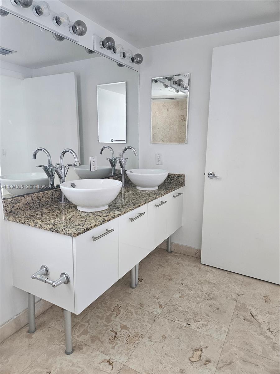 41 Southeast 5th Street, Unit 1517 Miami, FL 33131 - Photo 31 of 62 a bathroom with a granite countertop sink and a mirror