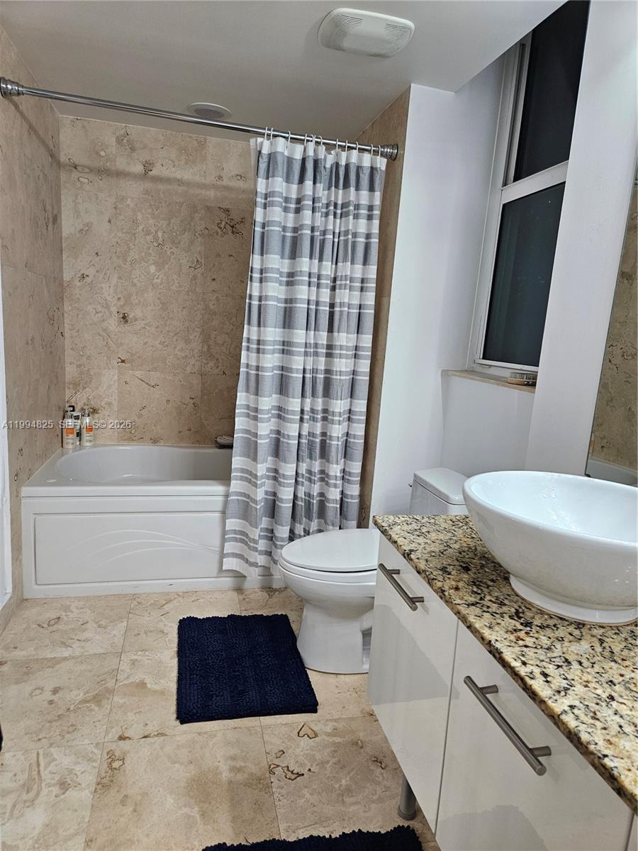 41 Southeast 5th Street, Unit 1517 Miami, FL 33131 - Photo 34 of 62 a bathroom with a granite countertop bathtub shower sink vanity and toilet