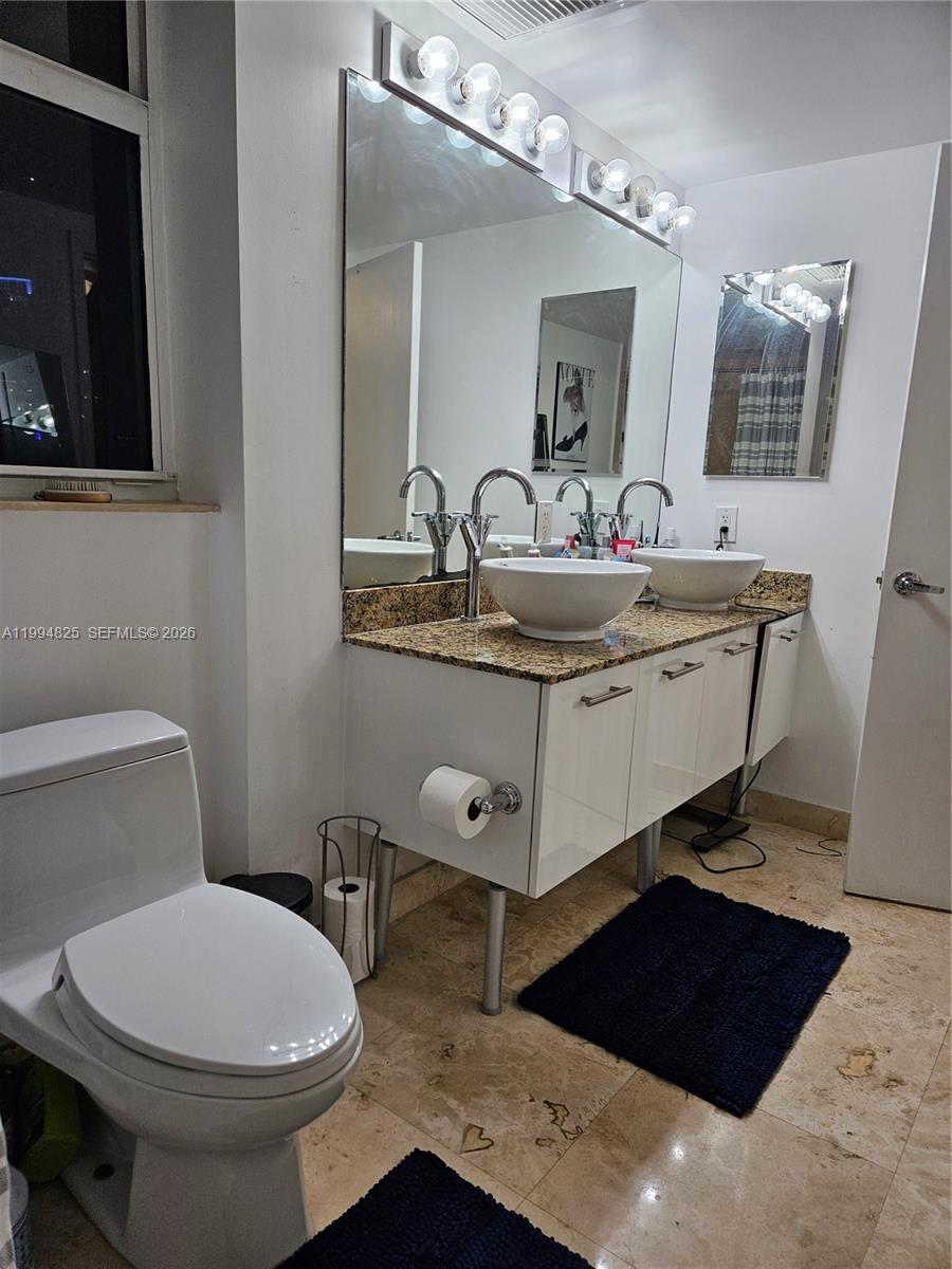 41 Southeast 5th Street, Unit 1517 Miami, FL 33131 - Photo 35 of 62 a bathroom with a toilet a sink and mirror
