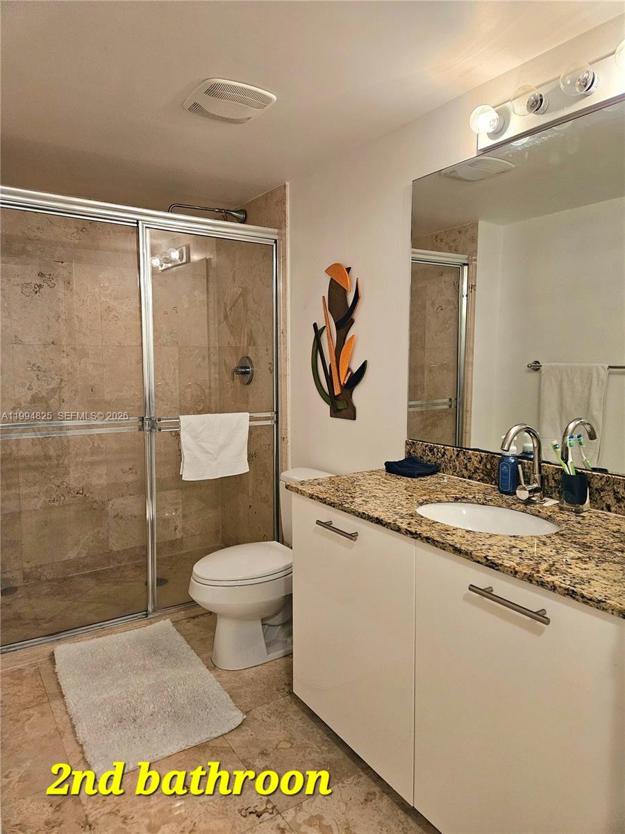 41 Southeast 5th Street, Unit 1517 Miami, FL 33131 - Photo 49 of 62 a bathroom with a granite countertop sink a toilet and a mirror