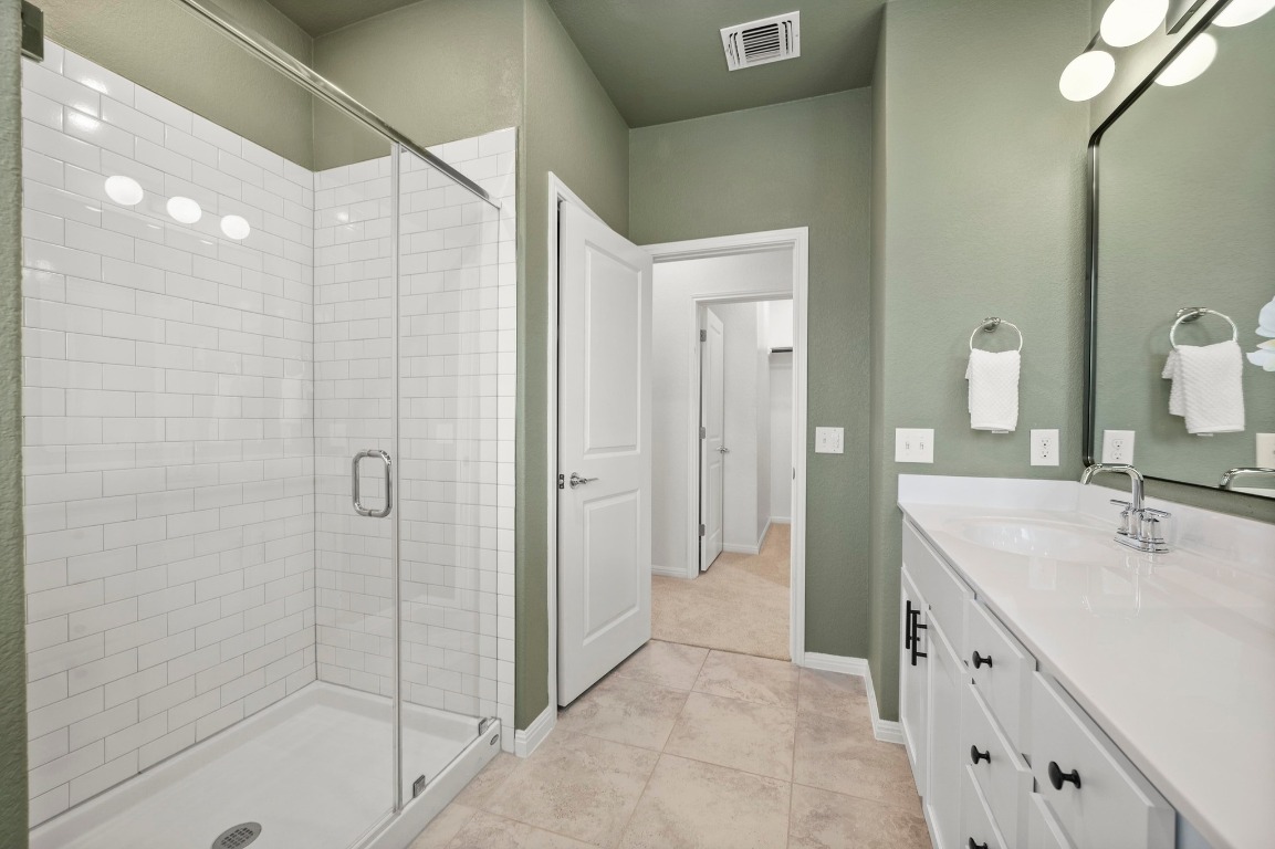 9015 Cattle Baron Path, Unit 2005 Austin, TX 78747 - Photo 16 of 37 a spacious bathroom with a double vanity sink a mirror and a shower