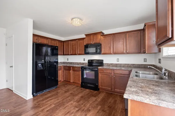 a kitchen with granite countertop wooden cabinets a stove a oven and a refrigerator with wooden floor