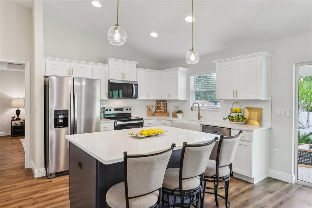 7217 Hemlock Loop Ocala, FL 34472 - Photo 15 of 36 a kitchen with a dining table chairs refrigerator and microwave