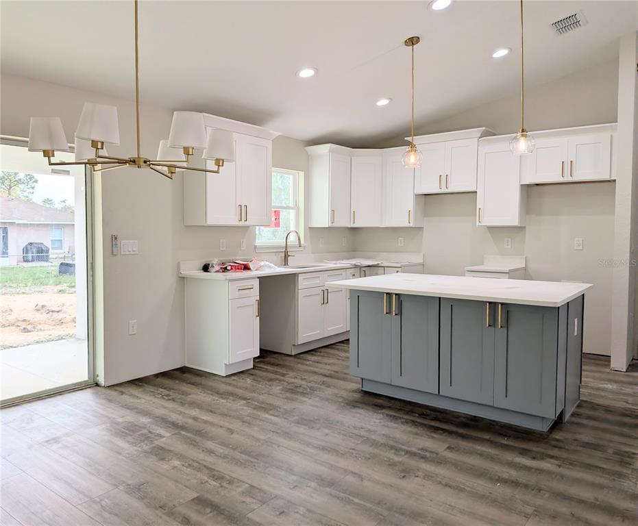 7217 Hemlock Loop Ocala, FL 34472 - Photo 3 of 36 a kitchen with stainless steel appliances granite countertop a sink a stove a refrigerator and island with wooden floor