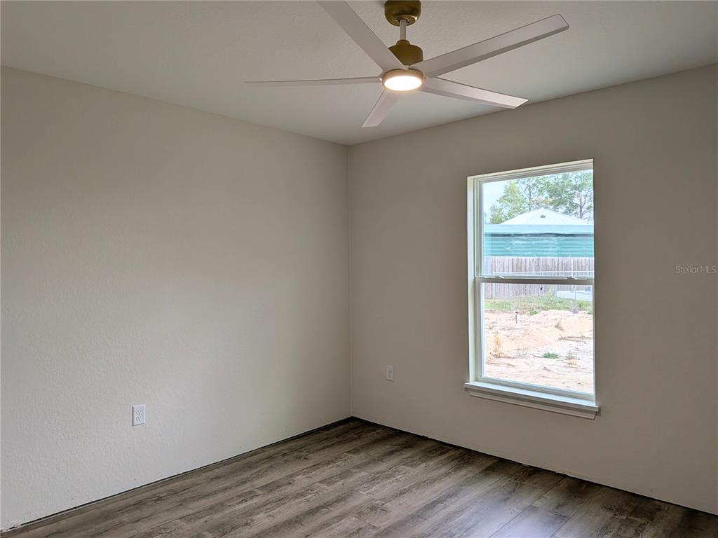 7217 Hemlock Loop Ocala, FL 34472 - Photo 10 of 36 an empty room with wooden floor ceiling fan and windows