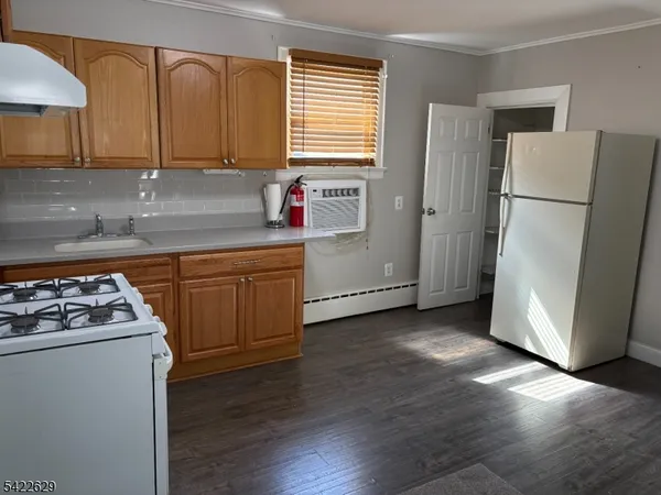 a kitchen with a refrigerator a stove a sink dishwasher and wooden cabinets with wooden floor