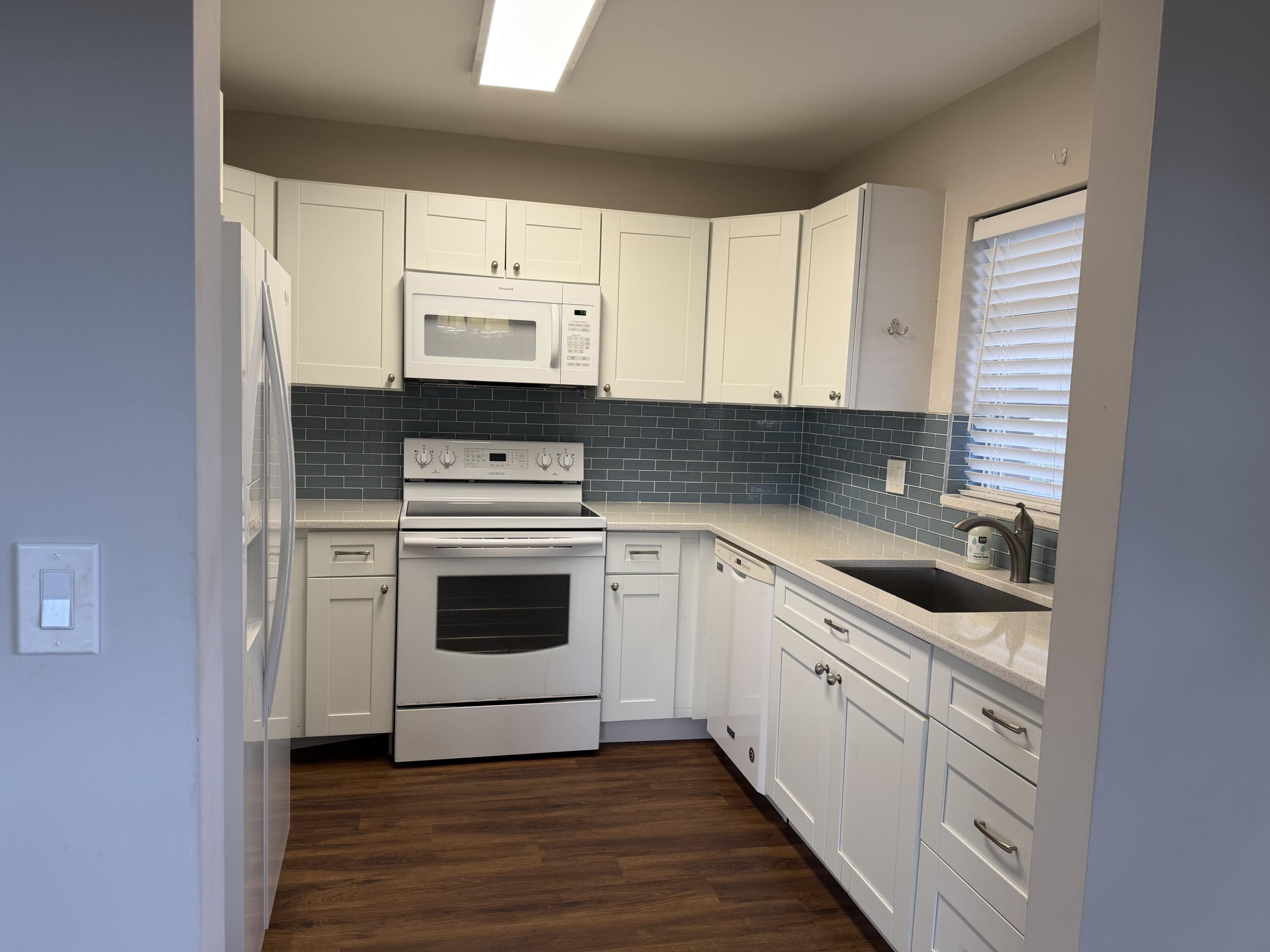 340 Orange Tree Drive, Unit 1 Atlantis, FL 33462 - Photo 11 of 23 a kitchen with white cabinets stainless steel appliances and sink