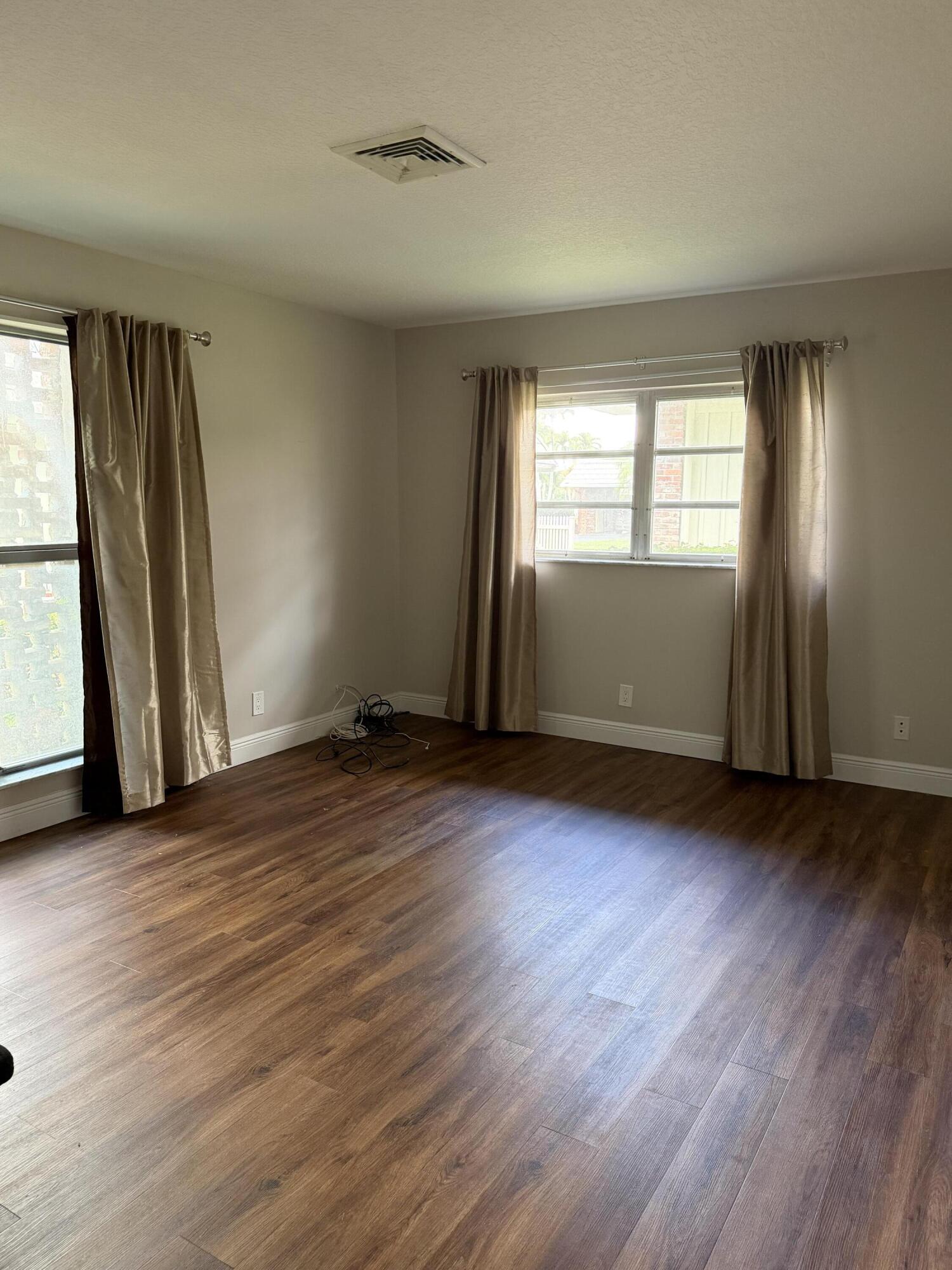 340 Orange Tree Drive, Unit 1 Atlantis, FL 33462 - Photo 14 of 23 an empty room with wooden floor and windows