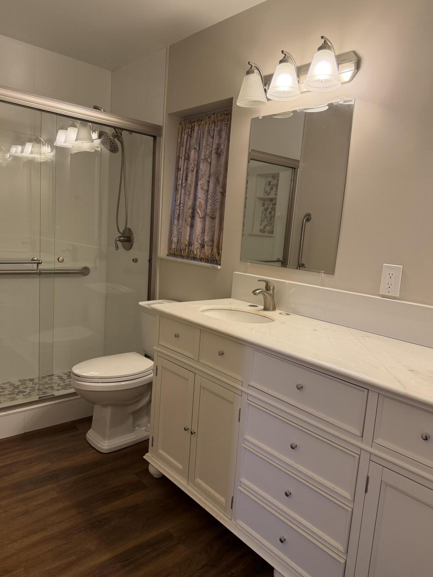 340 Orange Tree Drive, Unit 1 Atlantis, FL 33462 - Photo 18 of 23 a bathroom with a toilet a sink and mirror