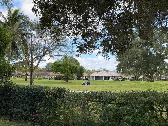 a view of grassy field with benches and trees all around