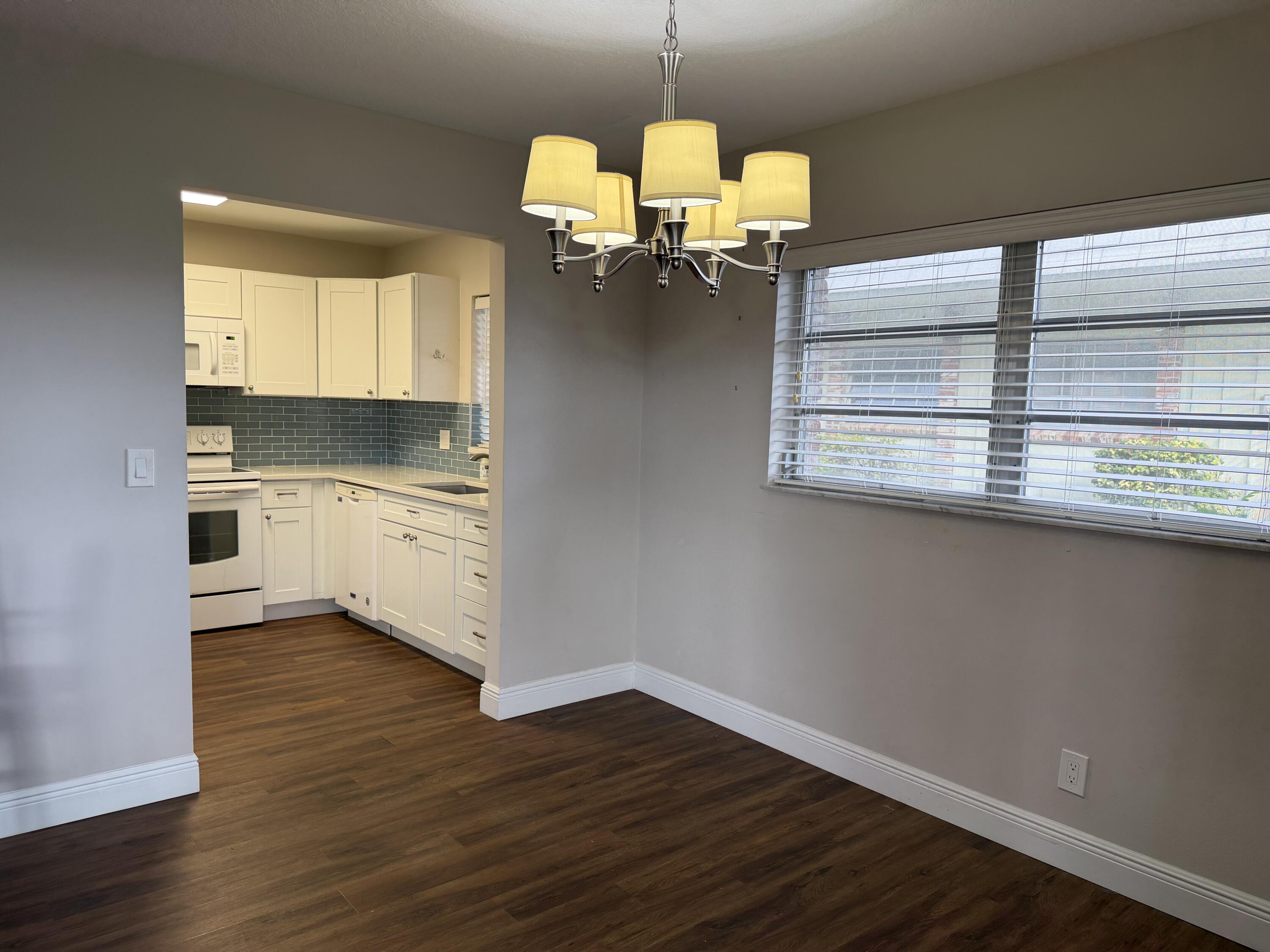 340 Orange Tree Drive, Unit 1 Atlantis, FL 33462 - Photo 10 of 23 a kitchen with kitchen island granite countertop a stove a sink and a wooden floors