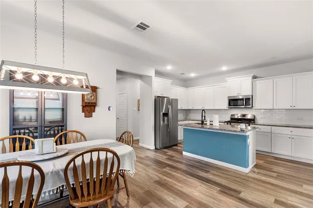 a kitchen with stainless steel appliances granite countertop a sink a stove a refrigerator cabinets and living room view