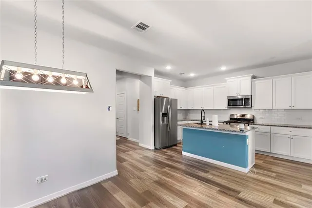 a kitchen with stainless steel appliances granite countertop a refrigerator and a stove top oven