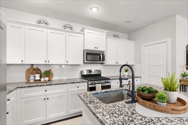 a kitchen with granite countertop a white cabinets and white appliances