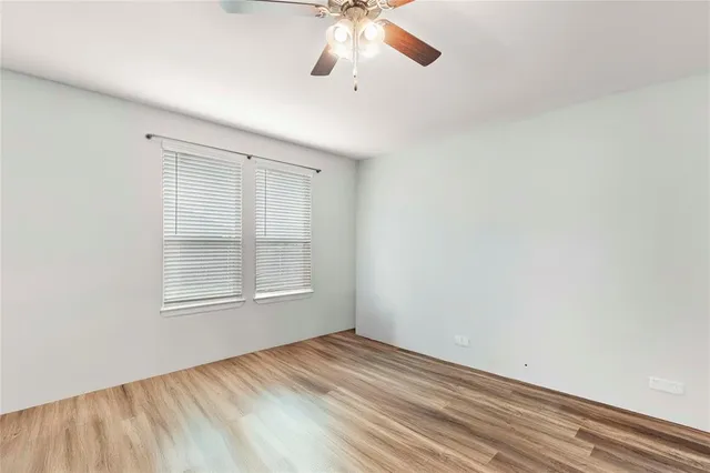 an empty room with a window and a ceiling fan