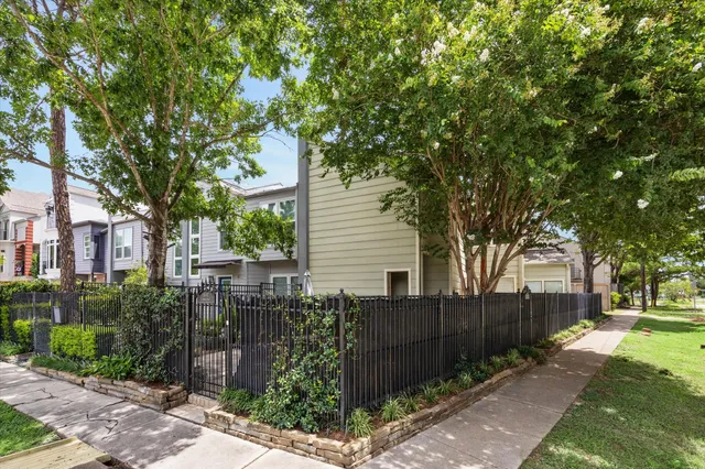 a backyard of a house with large trees and plants