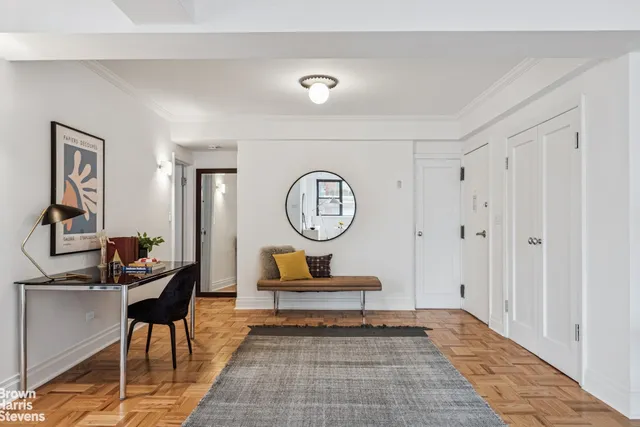 a living room with couch chairs and a large mirror next to a window