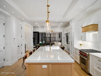 a room with stainless steel appliances kitchen island granite countertop a table chairs in it and wooden floors