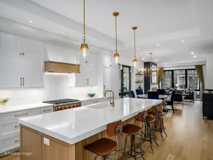 a kitchen with stainless steel appliances kitchen island granite countertop a table chairs stove and white cabinets