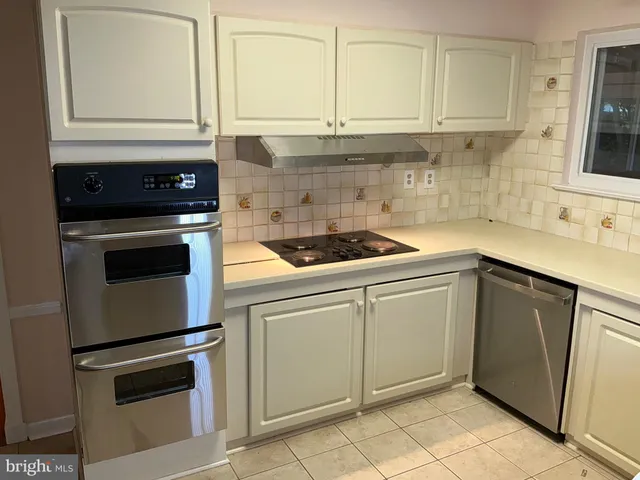 a kitchen with granite countertop white cabinets and black appliances
