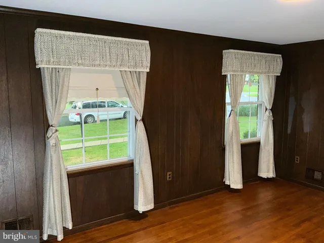 a view of an empty room with a window and wooden floor