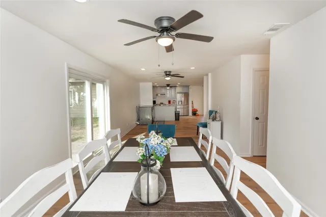 an empty room with wooden floor chandelier fan and windows