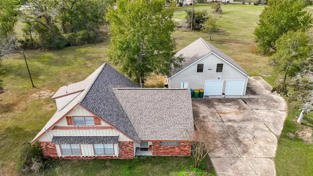 a aerial view of a house next to a yard with plants and large trees