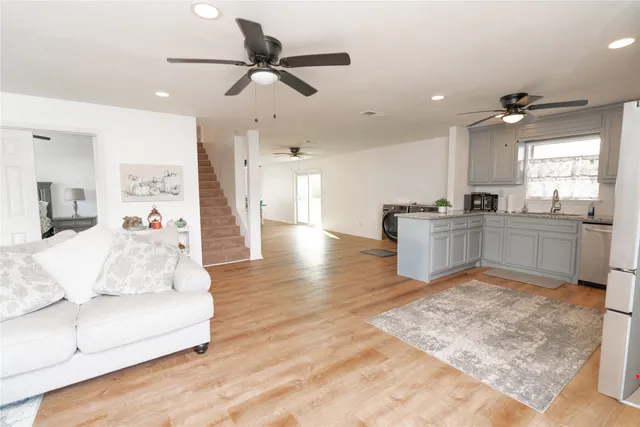 a view of a livingroom with furniture a ceiling fan and wooden floor