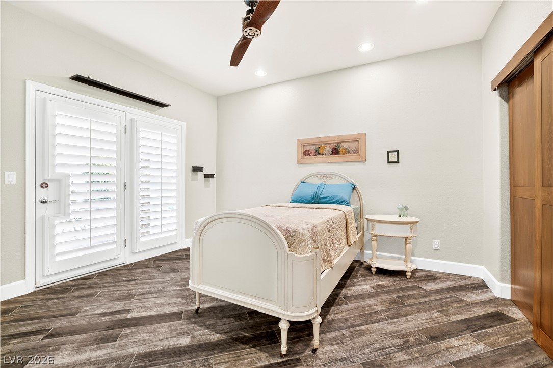1135 Calico Ridge Drive Henderson, NV 89011 - Photo 27 of 86 A well-lit downstairs bedroom featuring wood-look porcelain tile flooring and plantation-shuttered French doors to the yard and pool/spa.