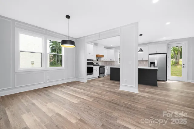 a view of a kitchen with refrigerator and wooden floor