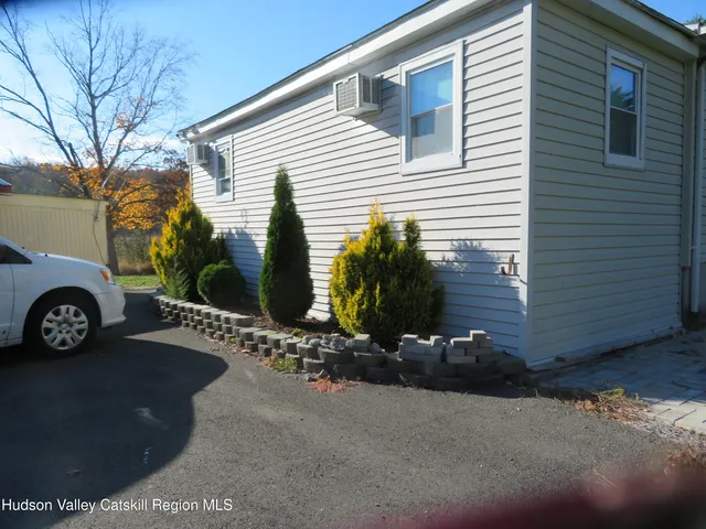 a view of a house with a small yard and parking space