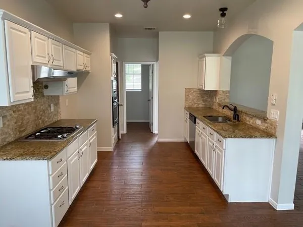 a kitchen with granite countertop a sink and a stove top oven