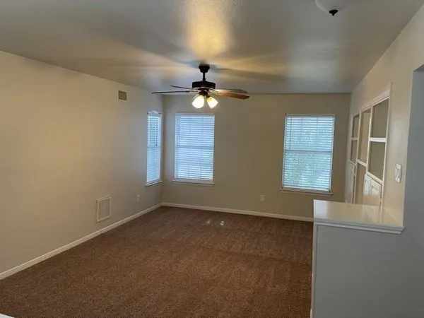 an empty room with windows and fan
