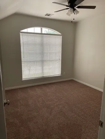 an empty room with a ceiling fan and window