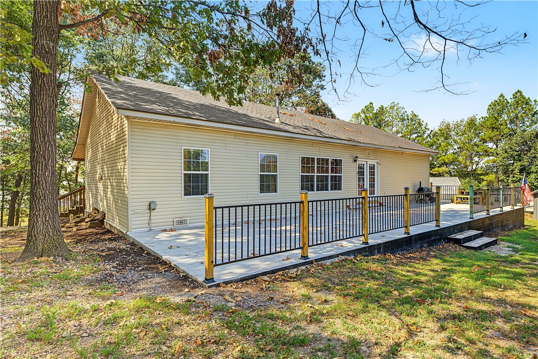 15282 Burgin Valley Road Gravette, AR 72736 - Photo 6 of 53 Expansive concrete patio featuring black metal railings with wooden posts, offering direct access via a double glass door